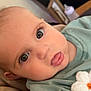 Luna is registered to the contest to win money with this photo: baby, infant, face, eyes, tongue, clothing, flower, green_outfit, closeup, indoor, couch, blanket, soft_furnishings, cute, child, person, portrait, skin, head, expression