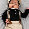 Isaac joined the competition — help win amazing prizes! baby, child, infant, cap, suspenders, black_shirt, beige_pants, lying_down, soft_surface, portrait, cute, fashion, clothing, face, headwear, person, young, indoors, expression, hands