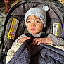 Isaac joined the competition — help win amazing prizes! baby, child, car_seat, hat, knit_hat, blanket, indoor, toddler, face, person, clothing, sitting, hands, eyes, warm, cozy, seatbelt, cute, portrait, infant