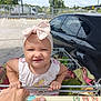 Avery joined the competition — help win amazing prizes! toddler, child, shopping_cart, headband, bow, parking_lot, car, hand, grip, clothing, outdoor, sunny, person, face, expression, grocery, retail, daytime, vehicle, baby