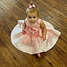 Meadow is registered to the contest to win money with this photo: baby, child, toddler, dress, pink_dress, bow, hair_bow, sitting, portrait, face, smiling, indoors, wooden_floor, hardwood, fashion, formalwear, infant, girl, full_body, photography
