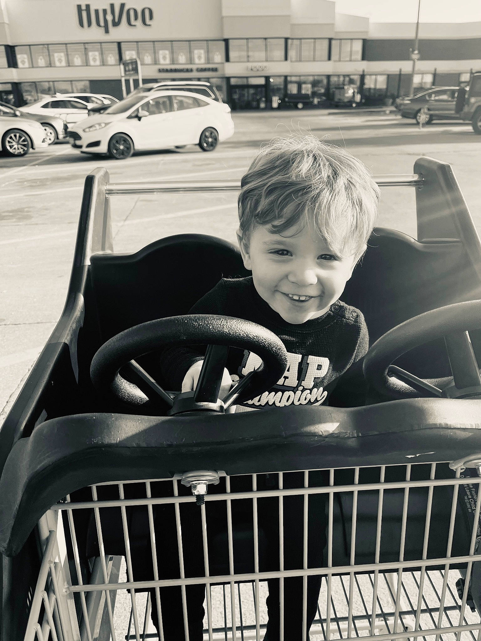 Jasper is registered to the contest to win money with this photo: automotive_design, automotive_exterior, automotive_lighting, automotive_tire, black, bumper, car, fender, grille, hood, joy, land_vehicle, mesh, motor_vehicle, person, photograph, smile, tire, toddler, vehicle