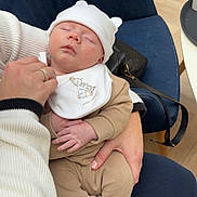 Reuben joined the competition — help win amazing prizes! baby, sleeping, infant, hat, clothing, hand, person, chair, blue_chair, floor, wood_floor, bib, socks, baby_clothes, indoor, nap, holding, peaceful, cute, cozy