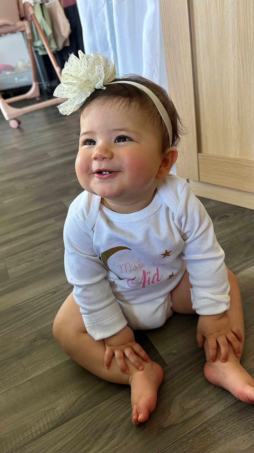 Adelaya participe au concours pour gagner de l'argent avec cette photo : baby, infant, child, headband, flower, smile, onesie, sitting, hardwood_floor, toes, hands, cheeks, indoor, wardrobe, stroller, clothing, portrait, cute, flooring, room