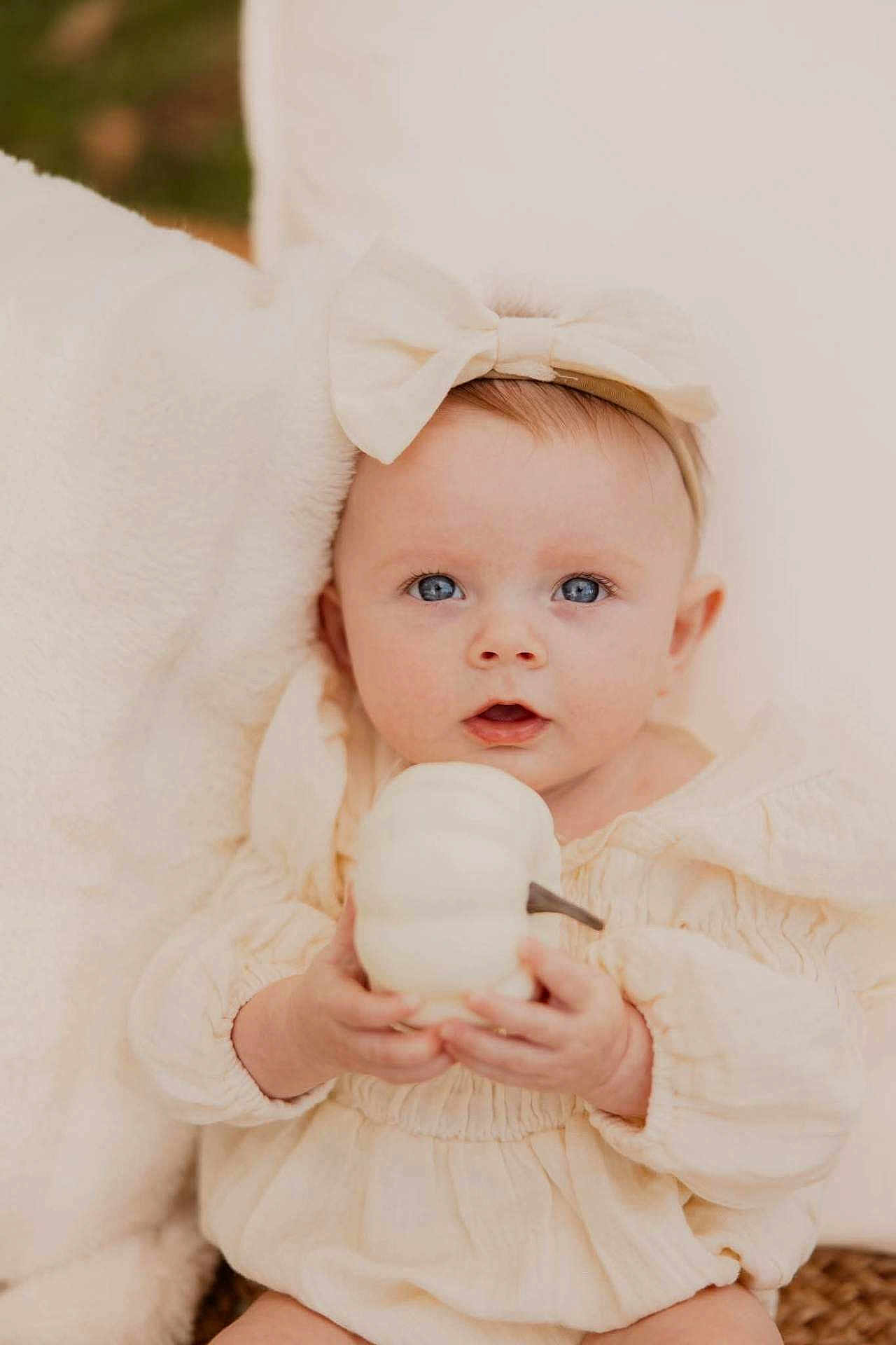 Ayla is registered to the contest to win money with this photo: baby, child, infant, blue_eyes, headband, bow, pumpkin, holding, soft_blanket, neutral_colors, cozy, portrait, cute, looking_at_camera, clothing, hands, skin, face, indoors, young