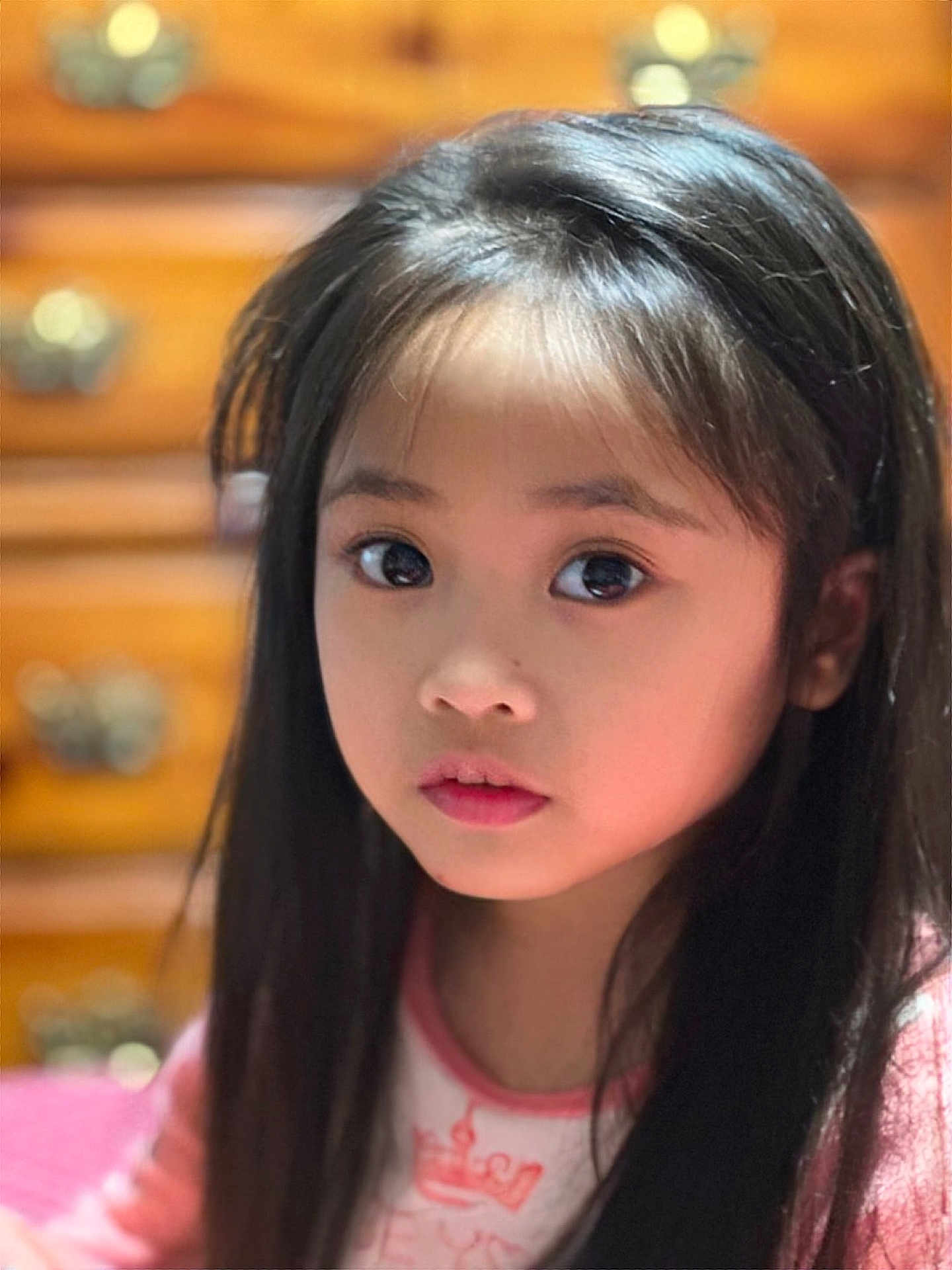 Alyna Bristol is registered to the contest to win money with this photo: black_hair, blurred_background, child, close-up, curious, drawer, expression, eyes, face, girl, hair, indoors, innocent, long_hair, person, pink_clothing, portrait, soft_lighting, warm_colors, young
