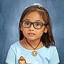 Alyna Bristol is registered to the contest to win money with this photo: blue_shirt, brown_hair, casual_clothing, child, childhood, curious_expression, earrings, face, fashion_accessory, girl, glasses, hair_bow, indoor, medallion, necklace, portrait, princess_print, short_sleeves, studio_background, young