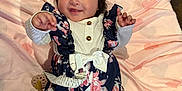 Arely joined the competition — help win amazing prizes! baby, infant, smiling, winking, floral_outfit, navy_blue, pink_blanket, hearts_pattern, lying_down, baby_toys, ruffles, cute, playful, child, indoors, soft_texture, headband, happy, person, portrait