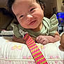 baby, butterfly_pattern, child, closeup, colorful_strap, cute, face, green_clothing, hand, happy, indoor, infant, lying_down, person, pillow, portrait, ruffled_sleeves, skin, smiling, young_child