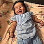 baby, smiling, infant, blue_clothing, blanket, cartoon_characters, lying_down, happy, cute, indoors, soft_texture, face, child, portrait, person, small_hands, cozy, bright, comfortable, sleepwear
