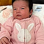 baby, infant, pink_onesie, bunny_design, cute, child, face, hair, hand, blanket, sleepwear, portrait, cozy, soft, indoor, young_child, adorable, expression, newborn, baby_girl