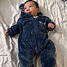 baby, blue_onesie, mickey_mouse, infant, bed, blanket, clothing, cute, face, fingers, footwear, fur_texture, hand, head, infant_clothing, lying_down, person, portrait, soft_texture, young_child