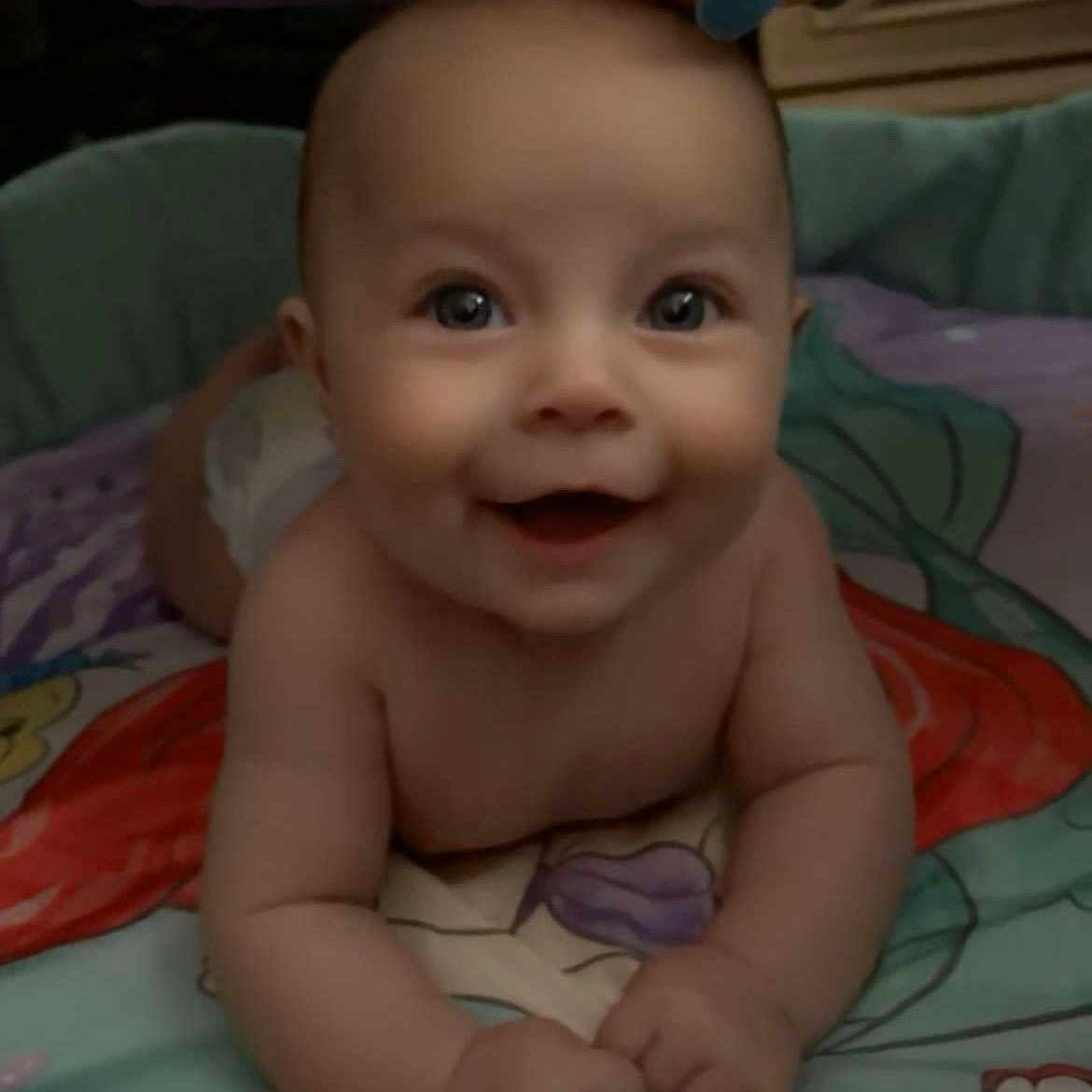 Willow is registered to the contest to win money with this photo: baby, cheerful, child, closeup, colorful, cute, expression, eyes, face, hands, happy, indoors, infant, lying_down, person, play_mat, portrait, skin, smiling, toddler