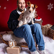 Lipton participe au concours pour gagner de l'argent avec cette photo : black_jacket, decorations, dog, festive, furry_surface, gift_boxes, holiday, indoor, jeans, man, pet, portrait, red_background, rocking_chair, santa_hat, smiling, snowflakes, teddy_bear, white_shoes, winter