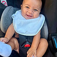 Noah joined the competition — help win amazing prizes! baby, smiling, car_seat, bib, happy, infant, child, cute, seatbelt, hands, feet, clothing, skin, person, safety, cute_expression, indoors, closeup, head, portrait