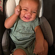 Noah is registered to the contest to win money with this photo: baby, baby_seat, child, cushion, cute, expression, face, fist, green_clothing, happy, indoor, infant, joy, onesie, person, portrait, seat, smiling, wearing, young_child