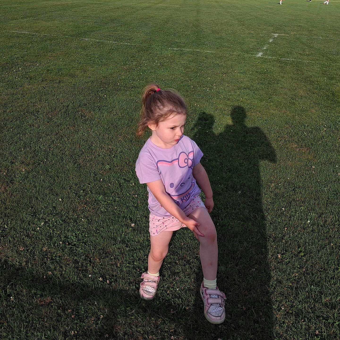 Ava is registered to the contest to win money with this photo: casual_clothing, child, daylight, field, girl, grass, hello_kitty, injury, knee, outdoor, people, person, photography, playing_field, shadow, shorts, sneakers, sports, sunlight, tshirt
