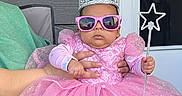 Aurora is registered to the contest to win money with this photo: adult_hand, baby, chair, child, costume, crown, door, dress, fashion, glitter, outdoor, patio, pink_dress, portrait, princess_costume, royalty, sparkles, star_wand, sunglasses, window