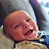 Tommy participe au concours pour gagner de l'argent avec cette photo : baby, smiling, infant, couch, blanket, indoors, happy, face, person, clothing, striped, soft, portrait, cute, child, home, relaxing, young, sitting, cozy
