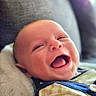 baby, smiling, happy, infant, blanket, couch, striped_clothing, face, portrait, indoors, child, soft_texture, comfort, relaxation, closeup, head, cute, expression, person, young