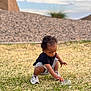 toddler, child, grass, rock, sneakers, outdoor, curious, black_shirt, shorts, nature, daylight, playing, crouching, young_child, person, portrait, casual_clothing, exploring, field, sunny
