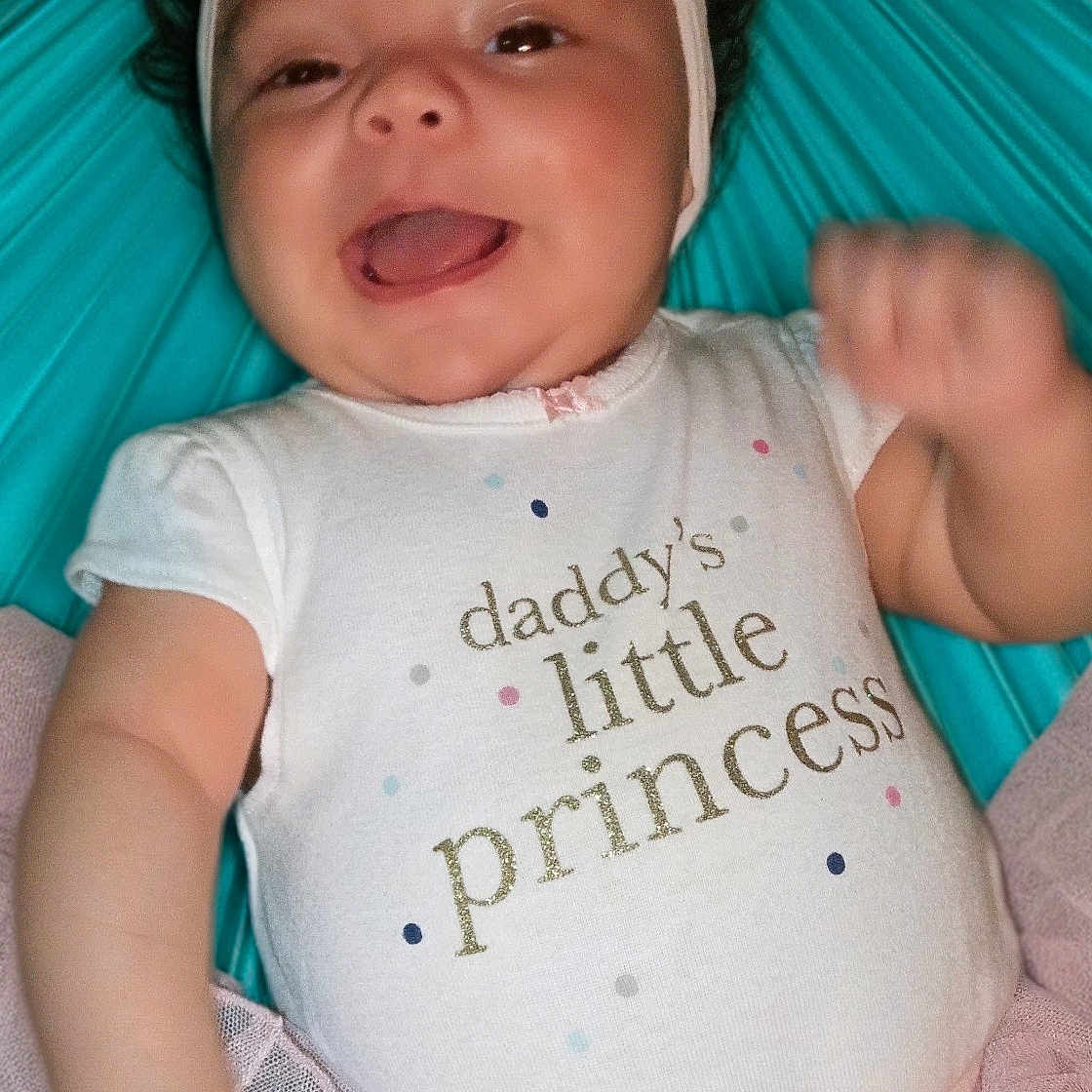 Neziah is registered to the contest to win money with this photo: baby, child, smiling, pink_bow, onesie, tutu, happy, cute, infant, portrait, sitting, clothing, headband, toddler, face, human, joyful, colorful_background, celebration, cheerful