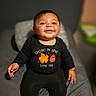 baby, child, infant, smiling, happy, portrait, sitting, black_outfit, onesie, clothing, bed, bedroom, indoor, close_up, face, eyes, hands, cozy, blurred_background, ai_generated_content