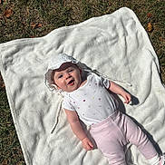 Romy a rejoint le concours — aidez-le/la à gagner de superbes lots ! baby, blanket, grass, sunlight, outdoor, child, hat, bonnet, clothing, pastel_colors, pink_pants, white_shirt, socks, shoes, smiling, face, person, sunglasses, playful, nature