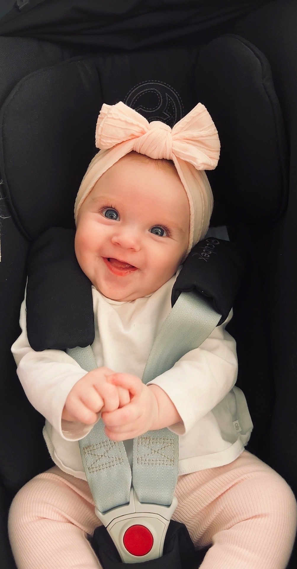 Romy participe au concours pour gagner de l'argent avec cette photo : baby, infant, child, car_seat, headband, bow, smiling, happy, blue_eyes, pink_clothing, white_shirt, safety_harness, cute, portrait, indoors, young_child, hands, seated, closeup, adorable