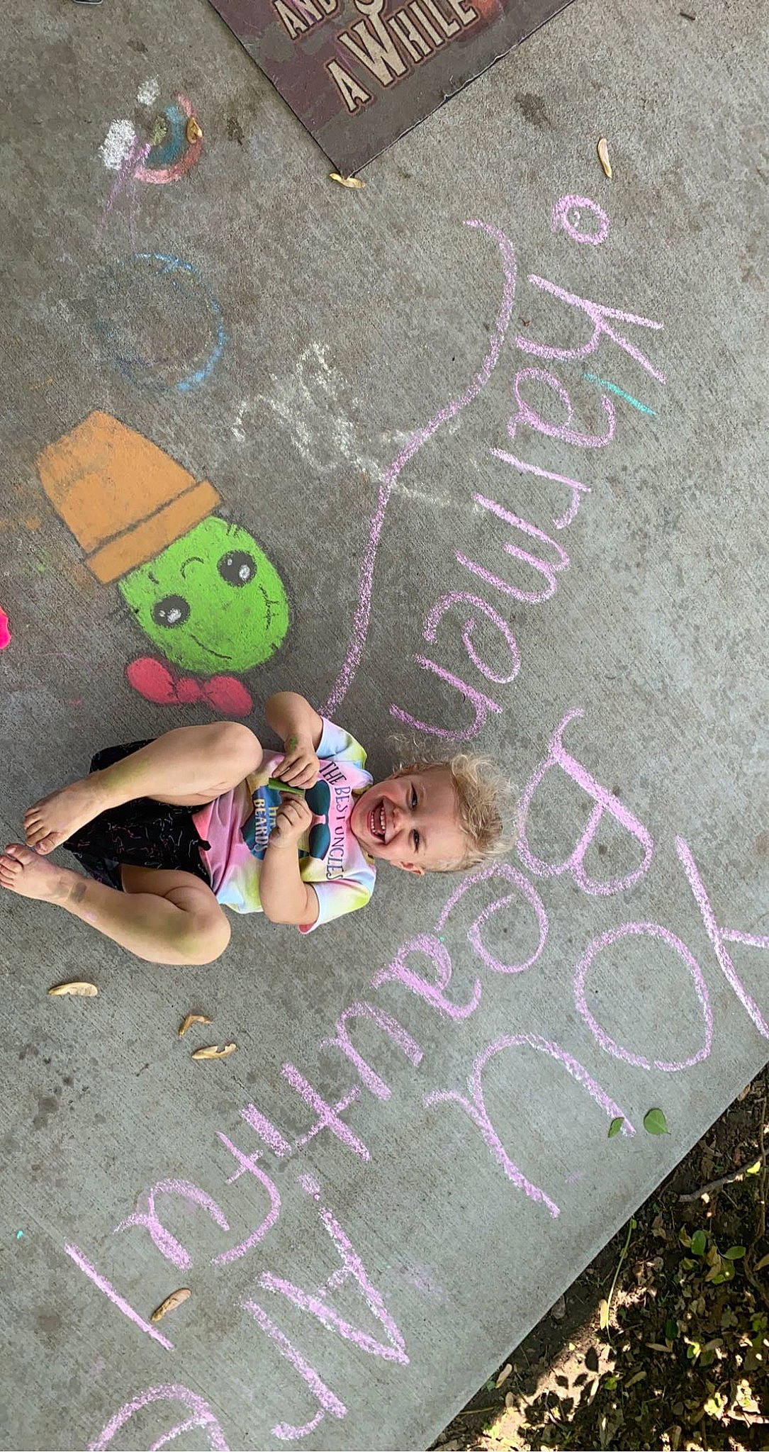 Karmen is registered to the contest to win money with this photo: art, asphalt, chalk, child, climbing_hold, concrete, drawing, font, grass, handwriting, happy, joy, organism, people, person, pink, public_space, road_surface, sidewalk, visual_arts