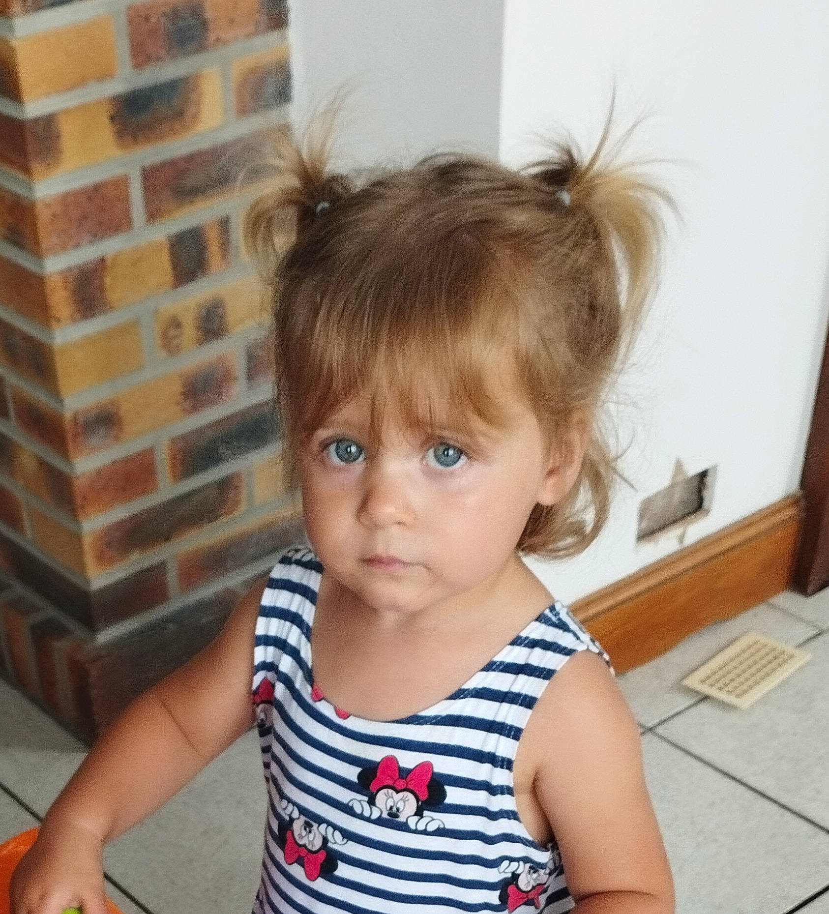 Julia participe au concours pour gagner de l'argent avec cette photo : baby, baby_toddler_clothing, bangs, brick, brickwork, cheek, child, eyelash, happy, iris, pattern, person, pigtail, sitting, sleeve, t_shirt, toddler, vacation, wood