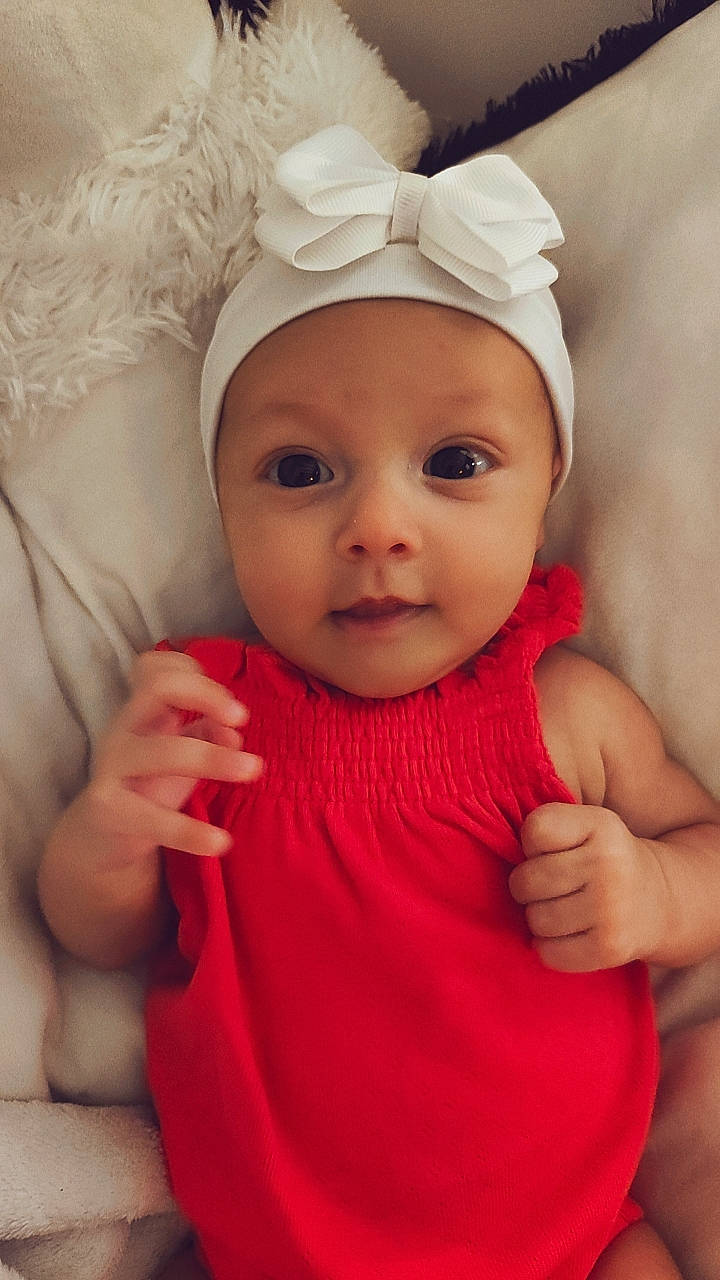 Kiara a rejoint le concours — aidez-le/la à gagner de superbes lots ! baby, baby_toddler_clothing, cheek, child, chin, dress, eye, facial_expression, gesture, happy, headwear, human_body, iris, lip, person, pink, skin, sleeve, smile, thumb