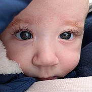 Arthur is registered to the contest to win money with this photo: baby, close_up, face, eyes, infant, child, winter_clothing, warm, cute, skin, eyelashes, nose, soft, portrait, young, person, expression, hood, fabric, innocence