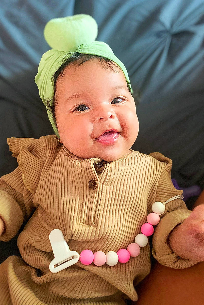 Kinsley is registered to the contest to win money with this photo: baby, baby_toddler_clothing, cap, cheek, child, chin, eye, facial_expression, finger, fun, hand, happy, human_body, lip, mammal, organ, person, pink, skin, smile