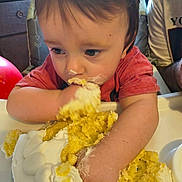 Dreyden is registered to the contest to win money with this photo: toddler, child, cake, food, messy, frosting, highchair, eating, hands, face, indoor, person, celebration, birthday, cream, yellow, red, shirt, happy, closeup
