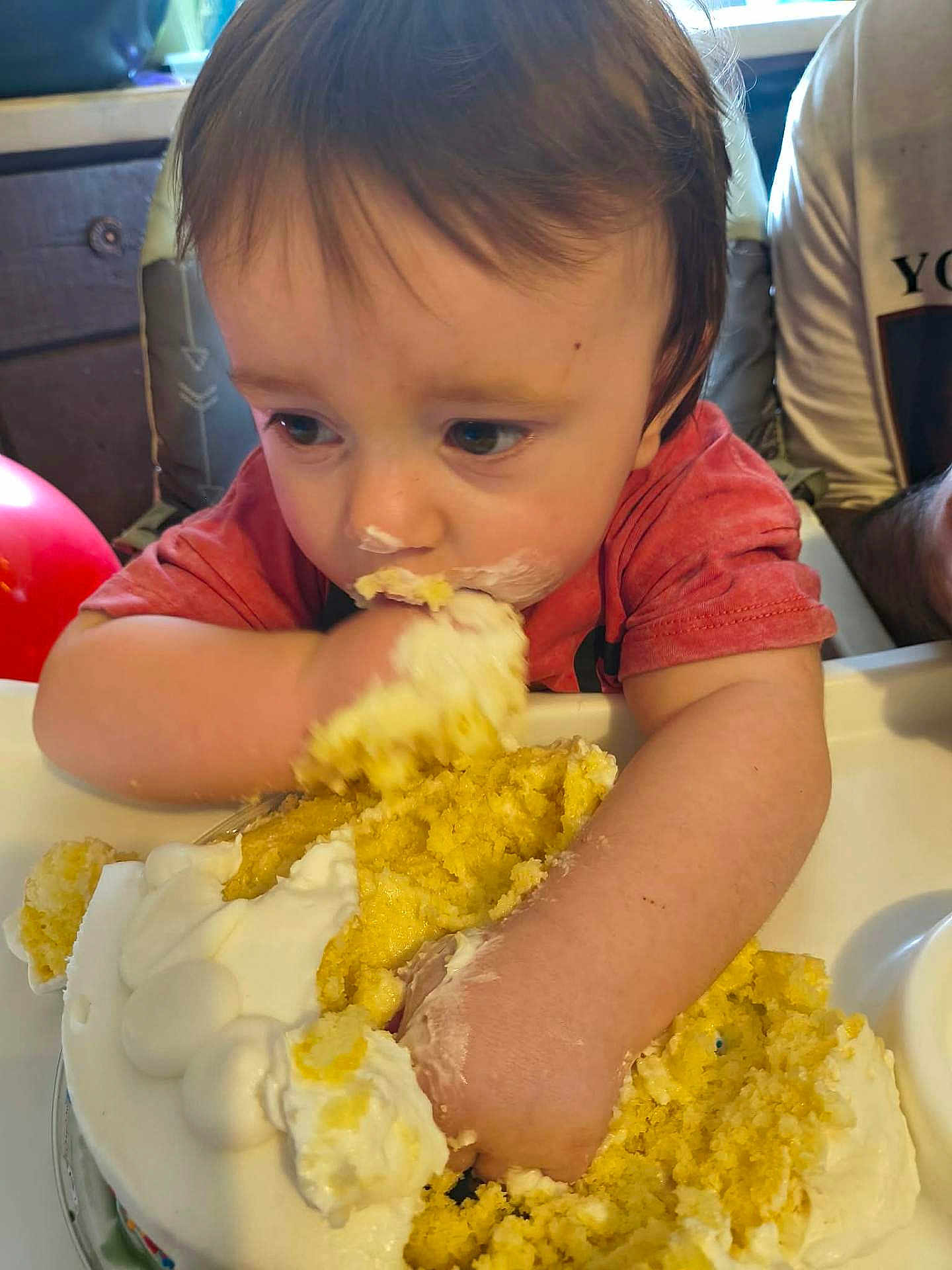 Dreyden is registered to the contest to win money with this photo: toddler, child, cake, food, messy, frosting, highchair, eating, hands, face, indoor, person, celebration, birthday, cream, yellow, red, shirt, happy, closeup