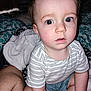 toddler, child, striped_shirt, bed, blanket, pillow, indoor, person, curious, wide_eyes, sitting, face, skin, short_hair, casual_clothing, closeup, expression, home, soft_lighting, baby