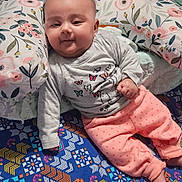 Zaynab joined the competition — help win amazing prizes! baby, blanket, butterfly_design, child, clothing, cozy, cute, floor, floral_pattern, indoors, infant, long_sleeve_shirt, patterned_blanket, person, pillow, polka_dot_pants, quilt, relaxed, smiling, soft_lighting