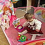 baby_gear, baby_toy, candid, child, colorful, curious, fairy_tale_characters, indoor, person, pink, plaid_dress, playing, playpen, polka_dot_tights, rainbow, seat, toddler, toy_laptop, white_lace, wooden_floor