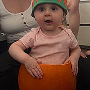 Scarlett joined the competition — help win amazing prizes! adult, autumn, baby, carving, child, costume, cute, floor, green, hands, hat, indoor, orange, person, pink_shirt, pumpkin, short_sleeves, smile, surprised, tattoo