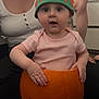 adult, autumn, baby, carving, child, costume, cute, floor, green, hands, hat, indoor, orange, person, pink_shirt, pumpkin, short_sleeves, smile, surprised, tattoo