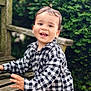 bench, casual_clothing, child, cute, daylight, foliage, greenery, happy, joyful, laughing, nature, outdoor, park, person, plaid_shirt, portrait, smiling, toddler, wood, young_child