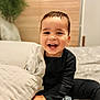 Kevin is registered to the contest to win money with this photo: toddler, child, smiling, happy, pajamas, bed, blanket, cushion, indoors, face, person, cozy, comfort, home, furniture, cute, young_child, portrait, sitting, baby