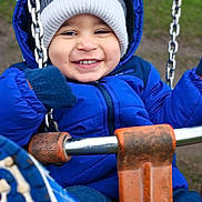 Kevin is registered to the contest to win money with this photo: blue_jacket, chains, child, cold_weather, cute, face, fun, gloves, happy, jacket, knit_hat, outdoor, park, person, playground, seat, smiling, swing, toddler, winter