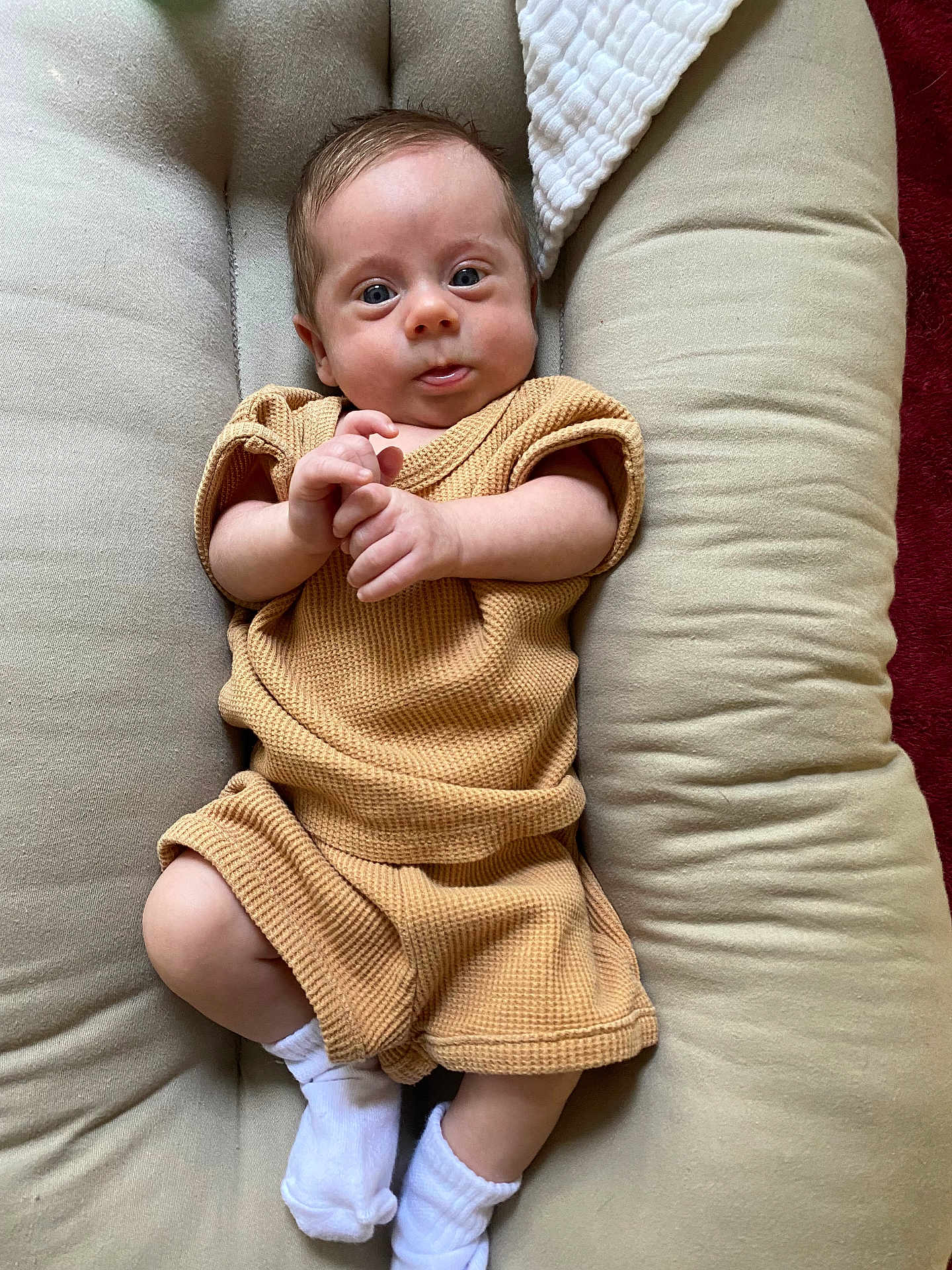 Theodore joined the competition — help win amazing prizes! baby, infant, child, person, cushion, clothing, sock, white_sock, beige_outfit, indoor, portrait, cute, small_hands, wide_eyes, soft_fabric, relaxed, lying_down, skin, head, face