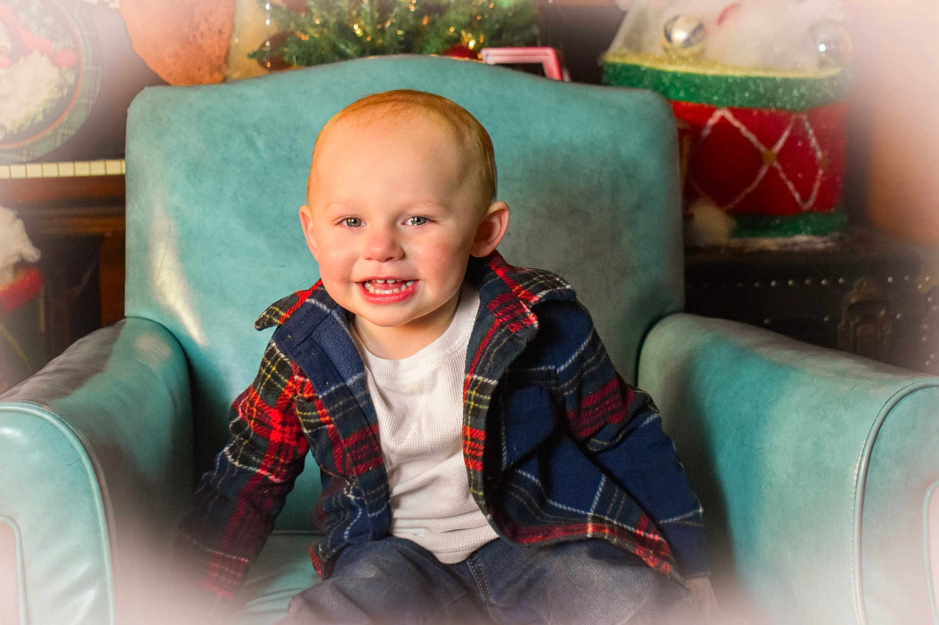 Jalen is registered to the contest to win money with this photo: toddler, child, smiling, plaid_jacket, white_shirt, teal_armchair, indoor, holiday_decor, christmas, festive, cute, happy, portrait, seated, young_child, warm_lighting, casual_clothing, red, blue, joyful