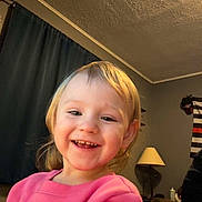 Brittney joined the competition — help win amazing prizes! child, toddler, smiling, happy, indoor, pink_sweatshirt, face, person, lamp, curtain, living_room, hair, clothing, sitting, young_child, cute, home, portrait, cheerful, expression