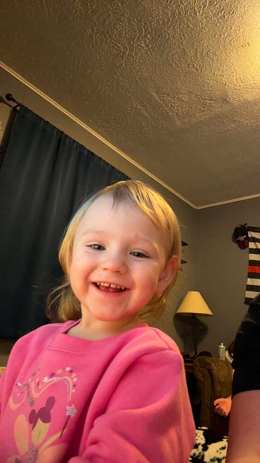Brittney joined the competition — help win amazing prizes! child, toddler, smiling, happy, indoor, pink_sweatshirt, face, person, lamp, curtain, living_room, hair, clothing, sitting, young_child, cute, home, portrait, cheerful, expression