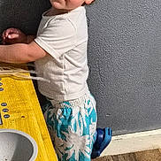 Monty is registered to the contest to win money with this photo: toddler, child, curly_hair, standing, play_kitchen, yellow_table, blue_crocs, shorts, white_tshirt, indoor, wood_floor, gray_wall, smiling, looking_back, young_child, casual_clothing, home, cute, playtime, portrait