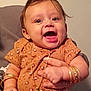 baby, child, smiling, jewelry, bracelets, necklace, hands, person, indoor, cute, happy, clothing, patterned_shirt, peach_pants, infant, portrait, human, young_child, accessories, holding